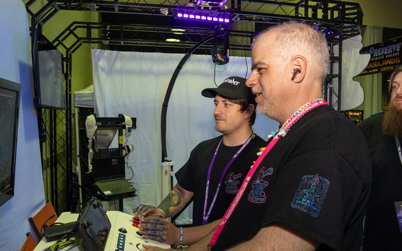 Pixel Forge Arcade convention booth with truss, purple lighting and VR stations